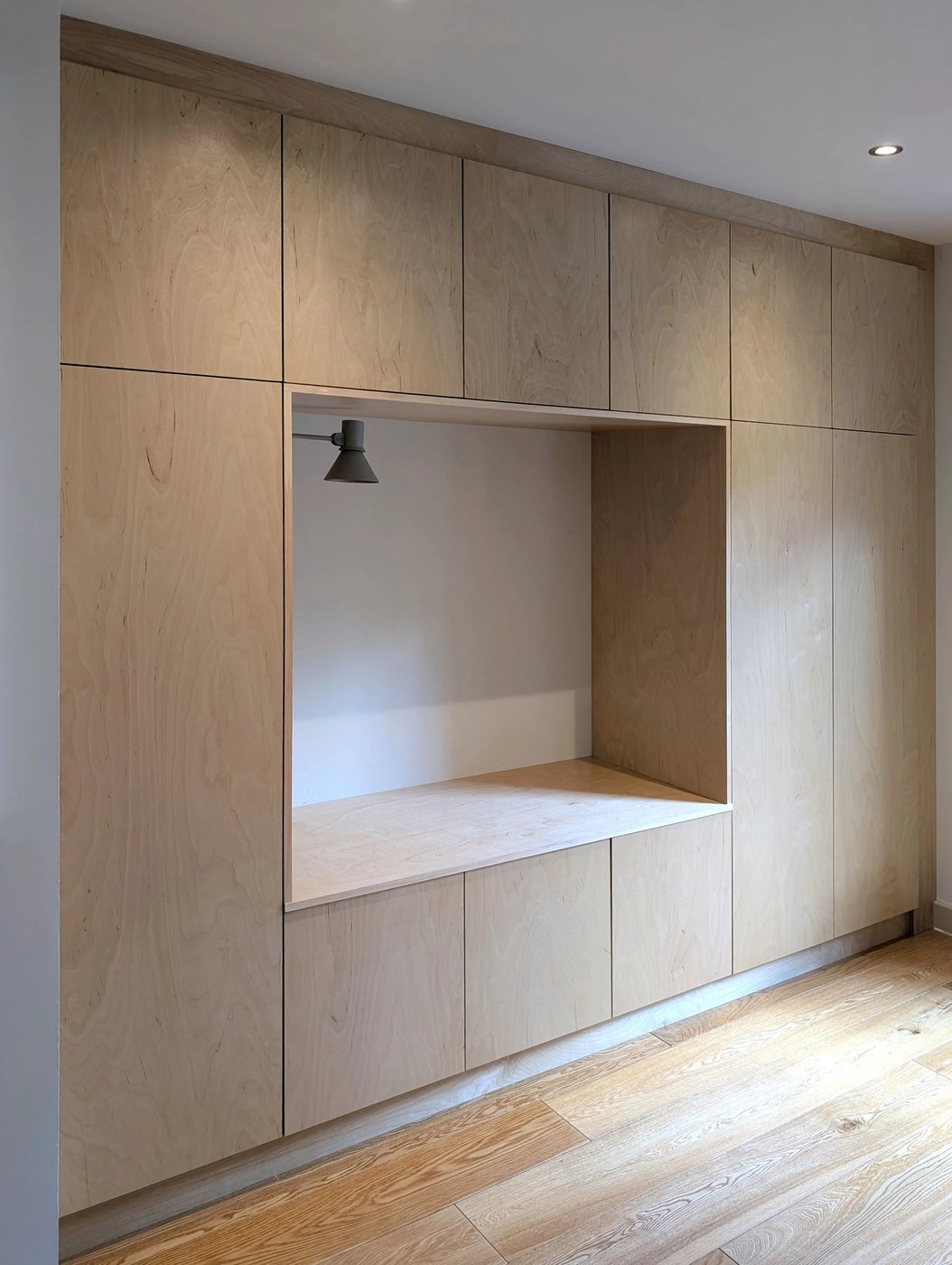 Full-height plywood joinery wall seen at an angle, showing the depth of the seating nook
