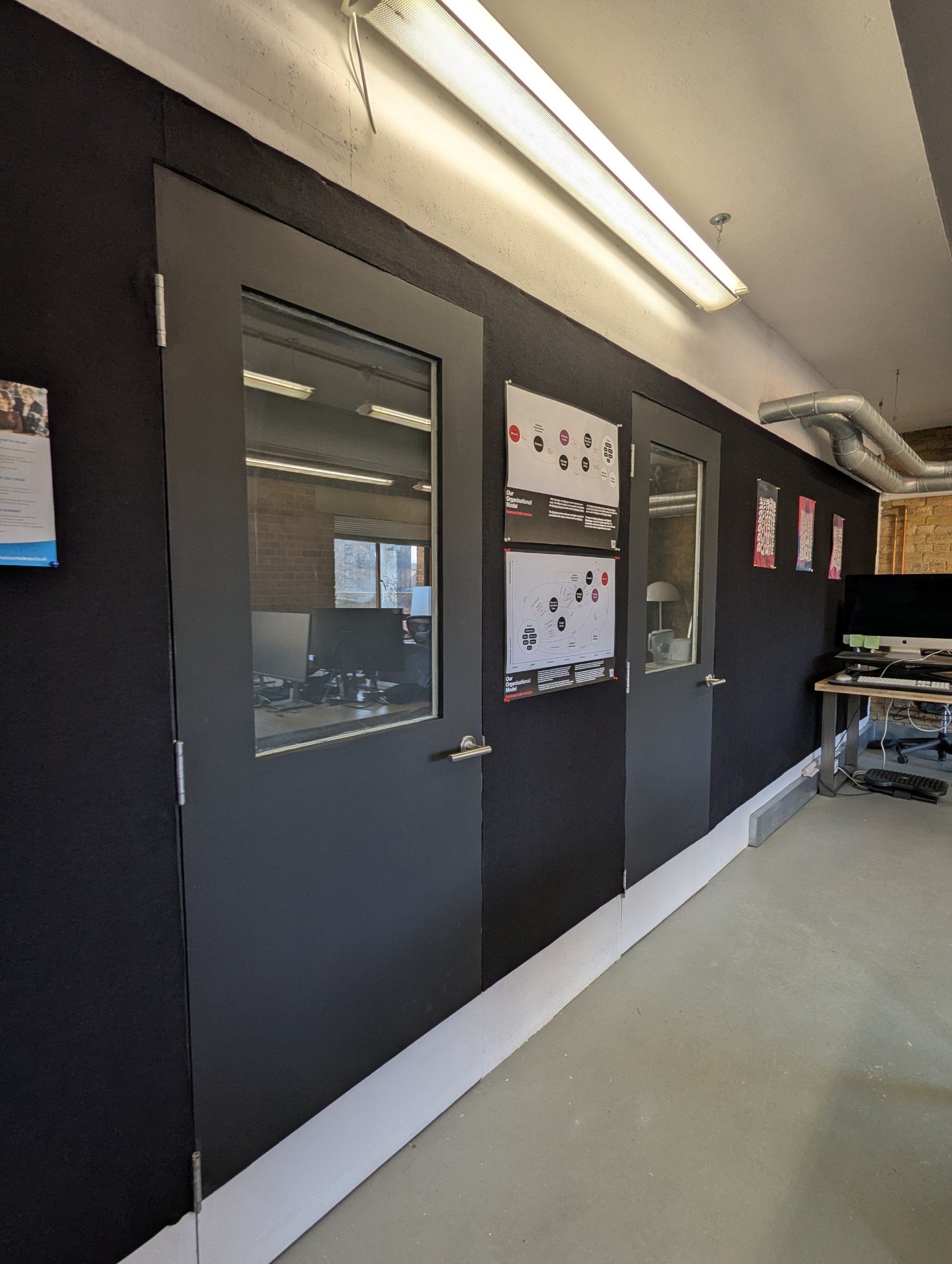 Closer view of the two meeting room doors, each with a glazed window, set into the black acoustic wool wall